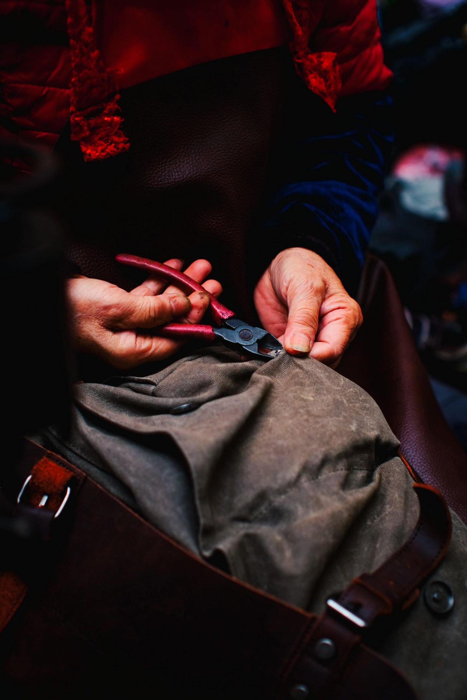 Leather care and repair: hands trimming a leather piece with shears on a work surface