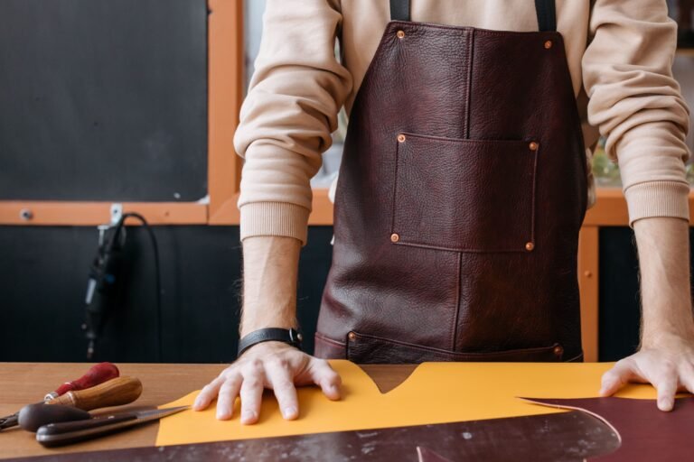 Person holding a brown leather bag in a workshop