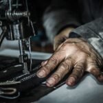 Worker's hands guiding leather through a stitching machine