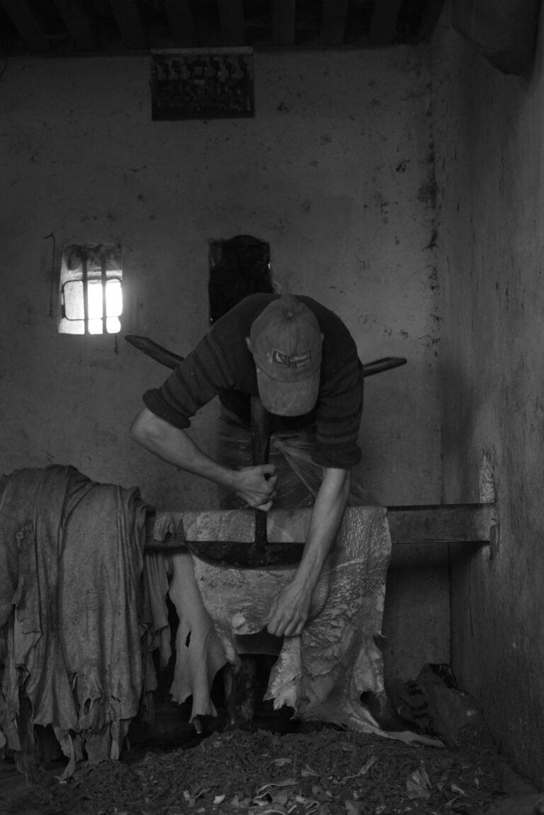 Black and white photo of an artisan hammering leather by hand