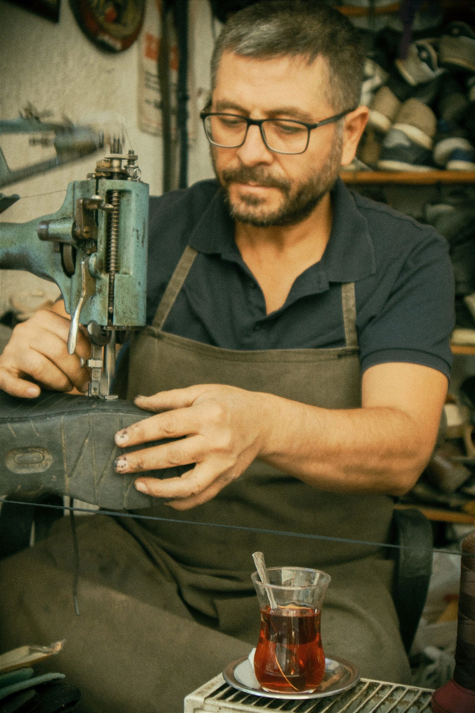 Craftsman in a green apron shaping leather by hand
