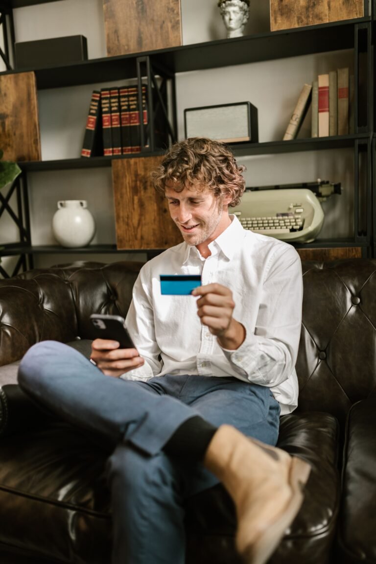 Man sitting on a brown leather sofa holding a card
